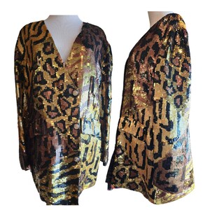 May include: A sequined blazer with a V-neck, featuring a gold, brown, and black animal print. The jacket has two front pockets and three gold buttons. The garment is displayed on a mannequin.