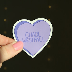 May include: A purple heart-shaped sticker with the text "Chaol Westfall" in white.