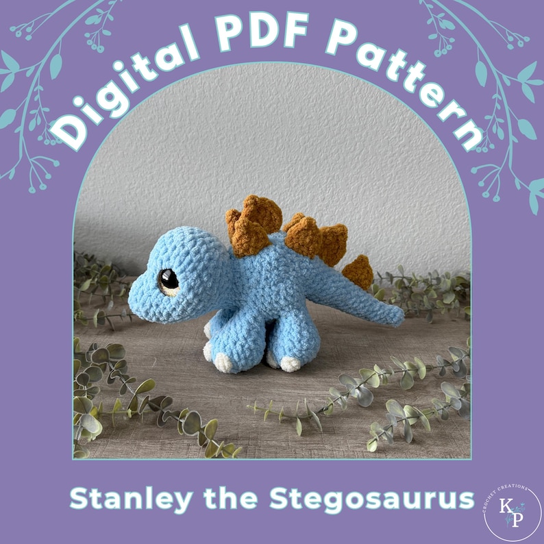 Op de afbeelding: Een gehaakt blauw stegosaurus speelgoed met bruine rugplaten. De afbeelding bevat de tekst "Digital PDF Pattern" en "Stanley the Stegosaurus". De achtergrond is een lichtgrijze muur en een houten oppervlak.