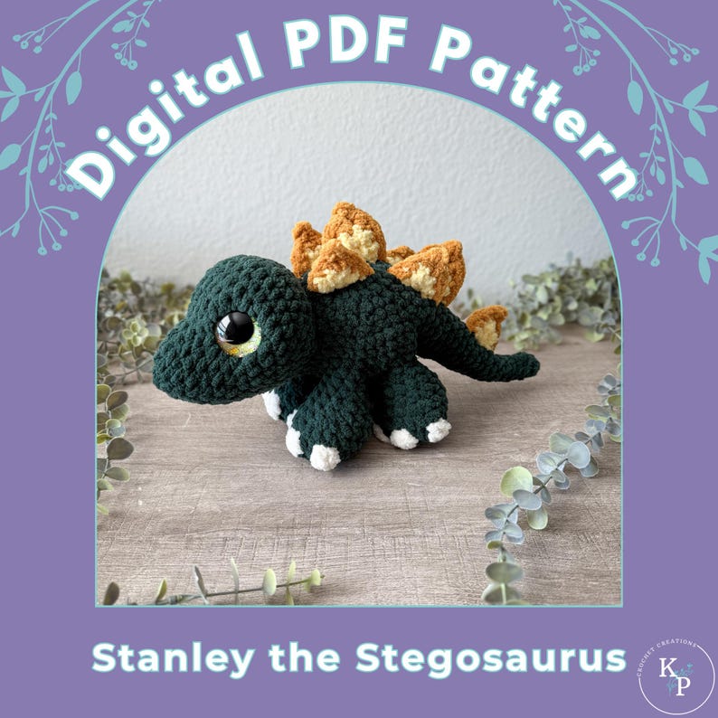 Op de afbeelding: Een gehaakt stegosaurus dinosaurus speelgoed in donkergroen met bruine en witte accenten. De dinosaurus heeft grote, ronde ogen en is gelabeld met "Stanley the Stegosaurus" met de tekst "Digital PDF Pattern" erboven.