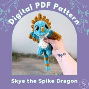 May include: A crochet plush toy of a dragon named Skye the Spike Dragon with blue, white, and brown yarn. The dragon has large dark eyes, a spiky crest, and wings. The image includes the text Digital PDF Pattern and Skye the Spike Dragon.