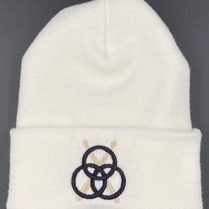 May include: White knit beanie with a black and tan embroidered design of three interlocking circles with crossed drumsticks.