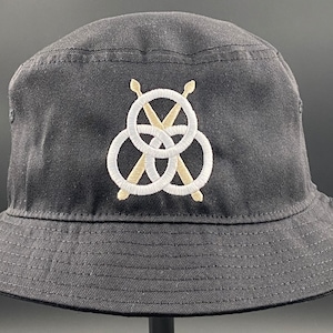 May include: A black bucket hat with a white and gold embroidered logo featuring three interlocking circles and two crossed drumsticks.