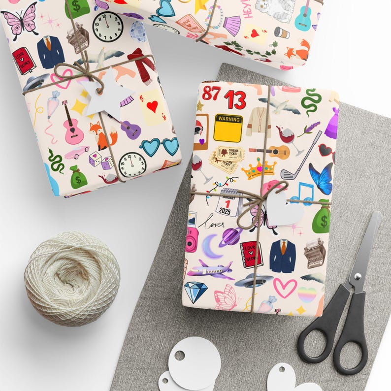 May include: Three gift wrap designs with a white background and colorful illustrations. The designs feature various icons, including butterflies, hearts, musical notes, a crown, a guitar, a camera, a plane, a UFO, a suitcase, a fox, a clock, a pair of sunglasses, a dice, a money bag, a snake, a wine glass, a golf club, a calendar, a book, a suit, a typewriter, and the text "Love Station" and "87 13".