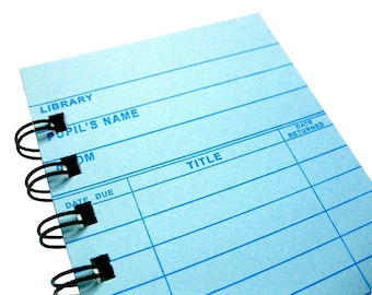 May include: A blue library card with the words "Library", "Pupil's Name", "Room", "Title", and "Date Returned" printed on it. The card has a spiral binding and is blank for filling in information.
