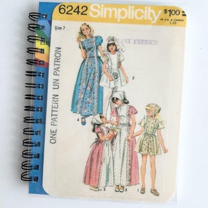 May include: A vintage Simplicity sewing pattern for girls' dresses. The pattern number is 6242 and the price is $100. The pattern includes four different dress styles, all with a vintage look. The dresses are in various colors and patterns, including blue, white, pink, and green.