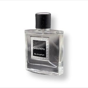 Puede incluir: Una botella de perfume de vidrio transparente con una tapa negra y una etiqueta plateada que dice "Casanova Eau de parfum".