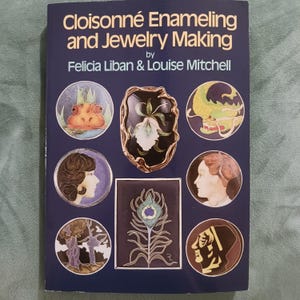 May include: A dark blue book titled Cloisonné Enameling and Jewelry Making by Felicia Liban & Louise Mitchell. The cover features various circular and rectangular illustrations of jewelry, including a flower, a dragon, and human profiles.