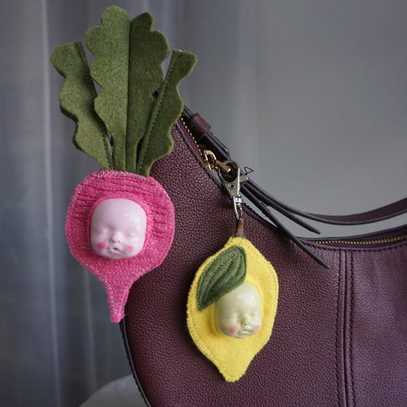 Handmade felt bag charms shaped like radishes, strawberries, and lemons — tiny, tactile, and oddly delightful on a keychain or tote.