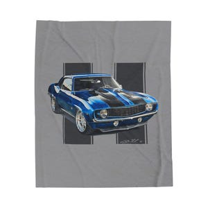 May include: A blue classic car with black racing stripes is depicted on a gray background. The car has chrome wheels and is a vintage model. The image is a print on a blanket.