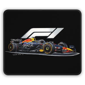May include: Black mouse mat with a Formula 1 race car design. The car is navy blue with red and yellow details, and the Oracle and Mobil logos are visible. The F1 logo is in the upper right corner.