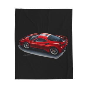 May include: A red sports car blanket with a detailed illustration of a red Ferrari. The car has a white, blue, and orange stripe down the center. The blanket is on a black background.