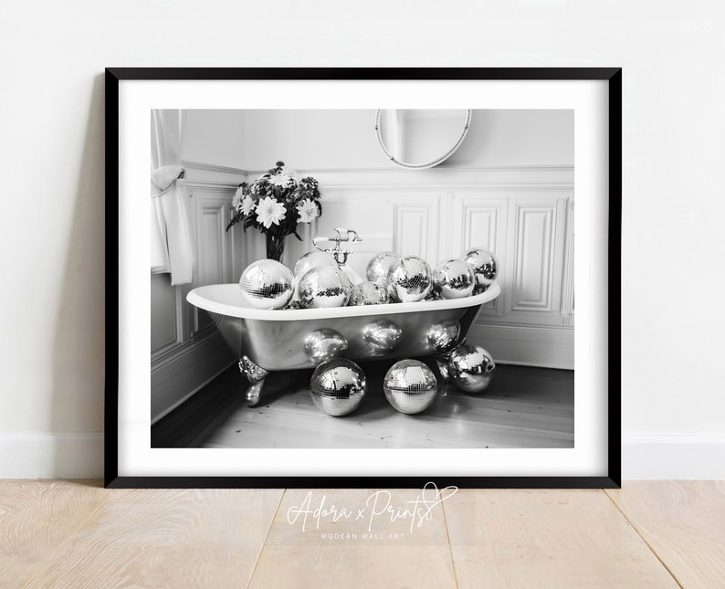 Puede incluir: Una fotograf&iacute;a en blanco y negro de una ba&ntilde;era llena de bolas de discoteca en un ba&ntilde;o con paredes blancas y un arreglo floral sobre una mesa.