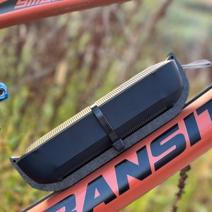 Side view of bluetooth speaker mounted to bicycle frame with extra securing reusable zip tie demonstrating durability and resistance to fall out.