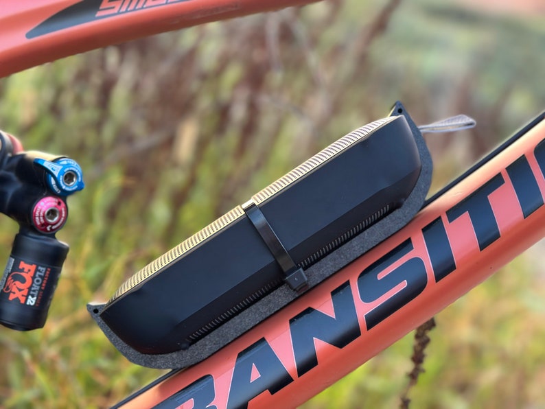 Side view of bluetooth speaker mounted to bicycle frame with extra securing reusable zip tie demonstrating durability and resistance to fall out.