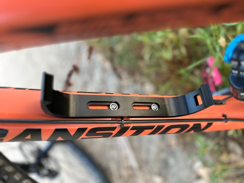Top view of audio speaker mounting bracket showing screws tightened to bicycle frame.