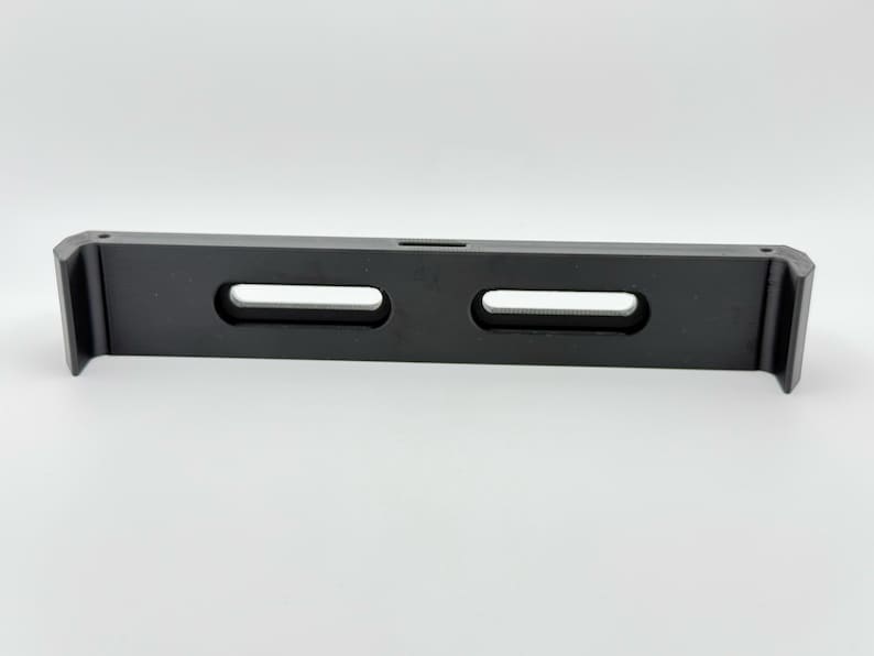 May include: A black plastic shelf bracket with two rectangular cutouts. The bracket is designed to support a shelf.