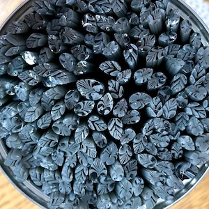 May include: A close-up view of a container filled with gray glass rods. The rods have a white, swirling pattern.