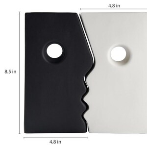Puede incluir: Jarr&oacute;n de cer&aacute;mica blanco y negro con dos caras, cada una con una abertura redonda. El jarr&oacute;n mide 8,5 pulgadas de alto y 4,8 pulgadas de ancho.