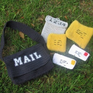 Könnte beinhalten: Eine schwarze gehäkelte Posttasche mit dem Wort "MAIL" in weißen Buchstaben. Die Tasche ist gefüllt mit kleinen gehäkelten Umschlägen, einige mit Zahlen und einige mit Linien.
