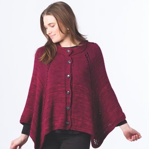 May include: A burgundy knitted poncho with a button closure and a lace pattern around the neckline and sleeves.