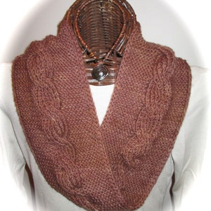 May include: A brown knitted infinity scarf with a cable knit pattern.