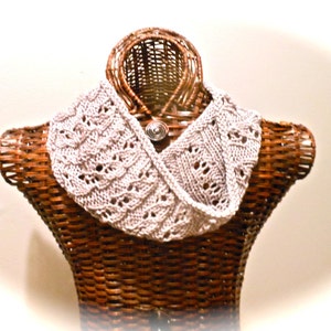 May include: A delicate, crocheted lace collar in a light beige color, displayed on a wicker mannequin.