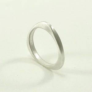 May include: A simple silver ring with a unique, slightly curved design. The ring is smooth and polished, with a brushed finish.