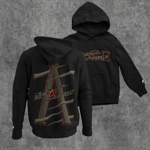 Può includere: Felpa con cappuccio nera con un design grafico sul retro che dice "Descend or Ascend" in testo rosso. La grafica è una lettera A stilizzata con linee marroni.