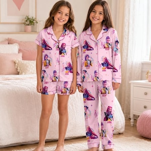 Può includere: Due set di pigiami rosa chiaro con un motivo ripetuto di personaggi dei cartoni animati e note musicali. Un set include una camicia a maniche corte con bottoni e pantaloncini, l'altro una camicia a maniche lunghe con bottoni e pantaloni lunghi.