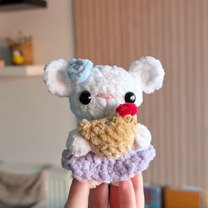 Peut inclure: Un ours en crochet blanc fait à la main avec un nœud bleu clair, des yeux noirs et un nez rose. L'ours tient un petit poulet en crochet beige avec une crête rouge. Il porte une jupe lavande. C'est un jouet mignon et fantaisiste.