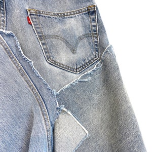 May include: A pair of light blue denim jeans with a distressed look. The jeans have a back pocket with a red tab and stitching around the edges.