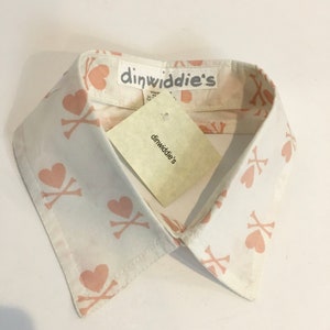 May include: White cotton shirt collar with a pink and white pattern of hearts and crossbones. The collar has a label that reads "dinwiddie's".