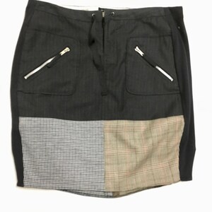 Puede incluir: Una falda de patchwork negra, gris y marrón con cintura de cordón y bolsillos con cremallera.