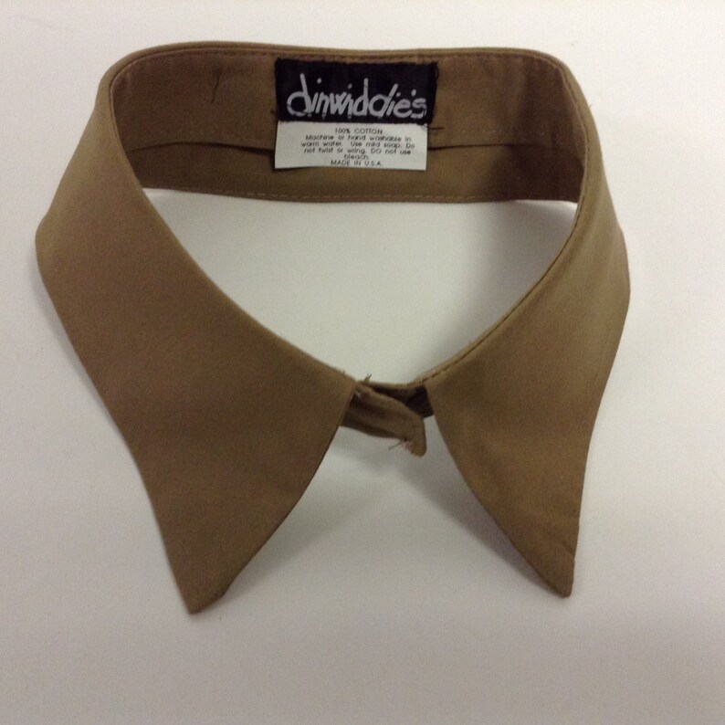 May include: A tan cotton shirt collar with a label that reads "Dinwiddies 100% Cotton Machine or hand wash in warm water. Use mild soap. Do not bleach. Do not use fabric softener. Made in USA."