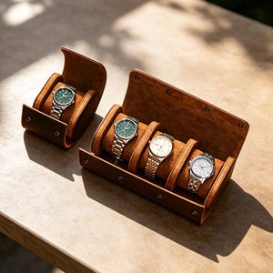 Könnte beinhalten: Ein Uhrenetui aus beigem Wildleder mit einer Armbanduhr mit grünem Zifferblatt und silbernem Armband sowie ein größeres Uhrenetui aus beigem Wildleder für drei Armbanduhren mit grünen, weißen und silbernen Zifferblättern und Metallarmbändern.