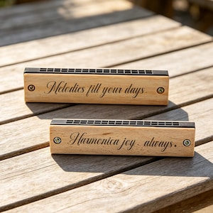 Peut inclure: Deux harmonicas en bois avec des peignes en métal noir. L'harmonica du haut est gravé avec le texte Melodies fill your days. Celui du bas porte l'inscription Harmonica joy. always. Les deux instruments présentent de petites vis métalliques.