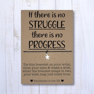 May include: A brown card featuring the text "If there is no STRUGGLE there is no PROGRESS". A black string with a silver star charm is attached. The card also includes instructions and the phrase "Handmade in the UK".