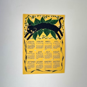 Kunstkalender 2026 | A4 geïllustreerde wandkalender met zwarte kat en bloemen | Handgetekende cartoon kat poster | Op de natuur geïnspireerde muurkunst