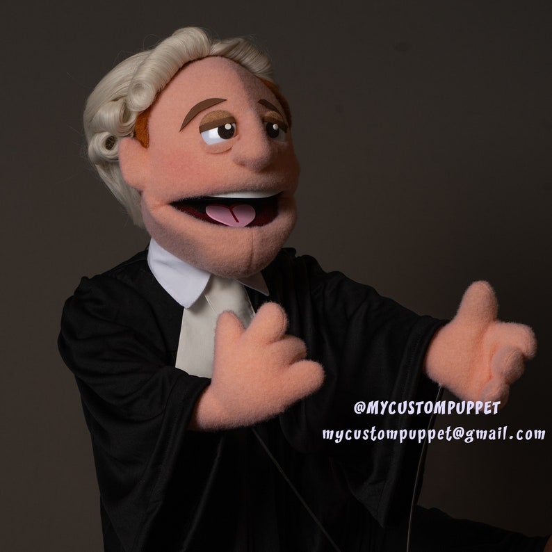 May include: A custom-made puppet dressed as a lawyer, wearing a black robe and a white wig. The puppet has a wide smile and is holding out its hands. The text '@MYCUSTOMPUPPET mycustompuppet@gmail.com' is visible in the bottom right corner of the image.