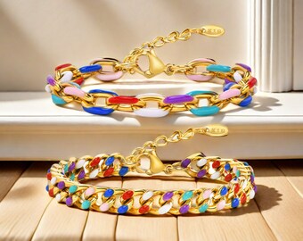 Puede incluir: Dos pulseras de cadena dorada con eslabones de esmalte de colores. Las pulseras están sobre una superficie de madera. La pulsera superior tiene eslabones de esmalte rosa, azul, rojo, morado y blanco. La pulsera inferior tiene eslabones de esmalte rosa, azul, rojo, morado y blanco en un patrón más aleatorio.
