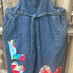 May include: A white ceramic mug with a black handle and the text "But First, Coffee" in a bold, black font. The mug is set against a blurred background, suggesting a cozy setting.