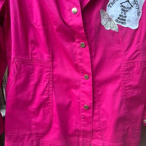 May include: A white ceramic mug with a black handle and the text "But First, Coffee" in a bold, black font. The mug is set against a blurred background, suggesting a cozy setting.