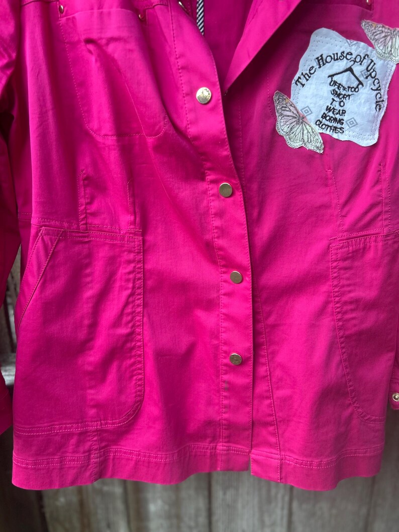 May include: A white ceramic mug with a black handle and the text "But First, Coffee" in a bold, black font. The mug is set against a blurred background, suggesting a cozy setting.