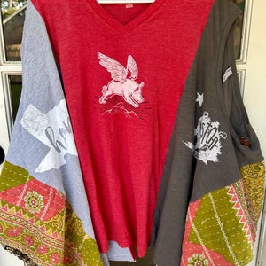 May include: A red, gray, and green patchwork top with a flying pig graphic. The top has a V-neck and is sleeveless. The fabric is a mix of cotton and silk.
