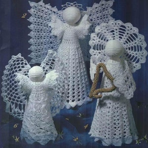 以下が含まれることがあります： レースの羽根を持つ、白い編みぐるみ天使が3体。中央の天使は直立しており、他の2体の天使は左右に配置され、一方は左向き、もう一方は右向き。右側の天使は金のハープを持っています。