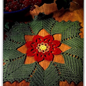 May include: A green crocheted doily with a red poinsettia in the center. The doily has a scalloped edge and a delicate lace pattern.