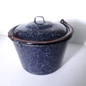 Peut inclure: Un seau en émail bleu marine moucheté avec un couvercle assorti. Le seau a une forme arrondie avec une poignée et un bord en métal. Le couvercle a une petite poignée en boucle. L'émail a un motif moucheté.