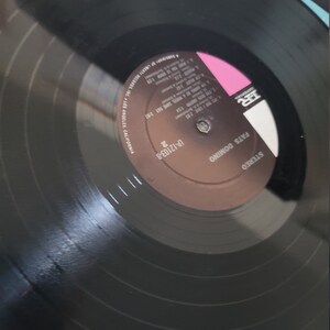 Puede incluir: Un disco de vinilo negro con el texto "Fats Domino" y "Stereo". La etiqueta del disco es marr&oacute;n y rosa, con t&iacute;tulos de canciones y duraciones. Un art&iacute;culo de m&uacute;sica vintage.