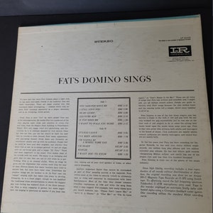 Puede incluir: Portada de &aacute;lbum de vinilo LP vintage "Fats Domino Sings". La portada del &aacute;lbum es blanquecina con texto negro y un borde azul claro. El &aacute;lbum presenta una lista de canciones en la parte posterior.